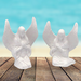 Ready to paint ceramic angel figurines sitting on a rustic table near the ocean.